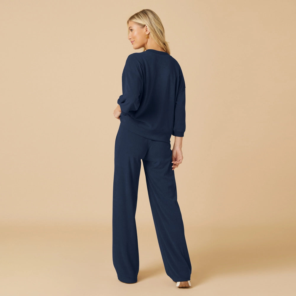 A woman from behind wearing a navy blue terry cropped sleeve crew neck and wide leg pant set.