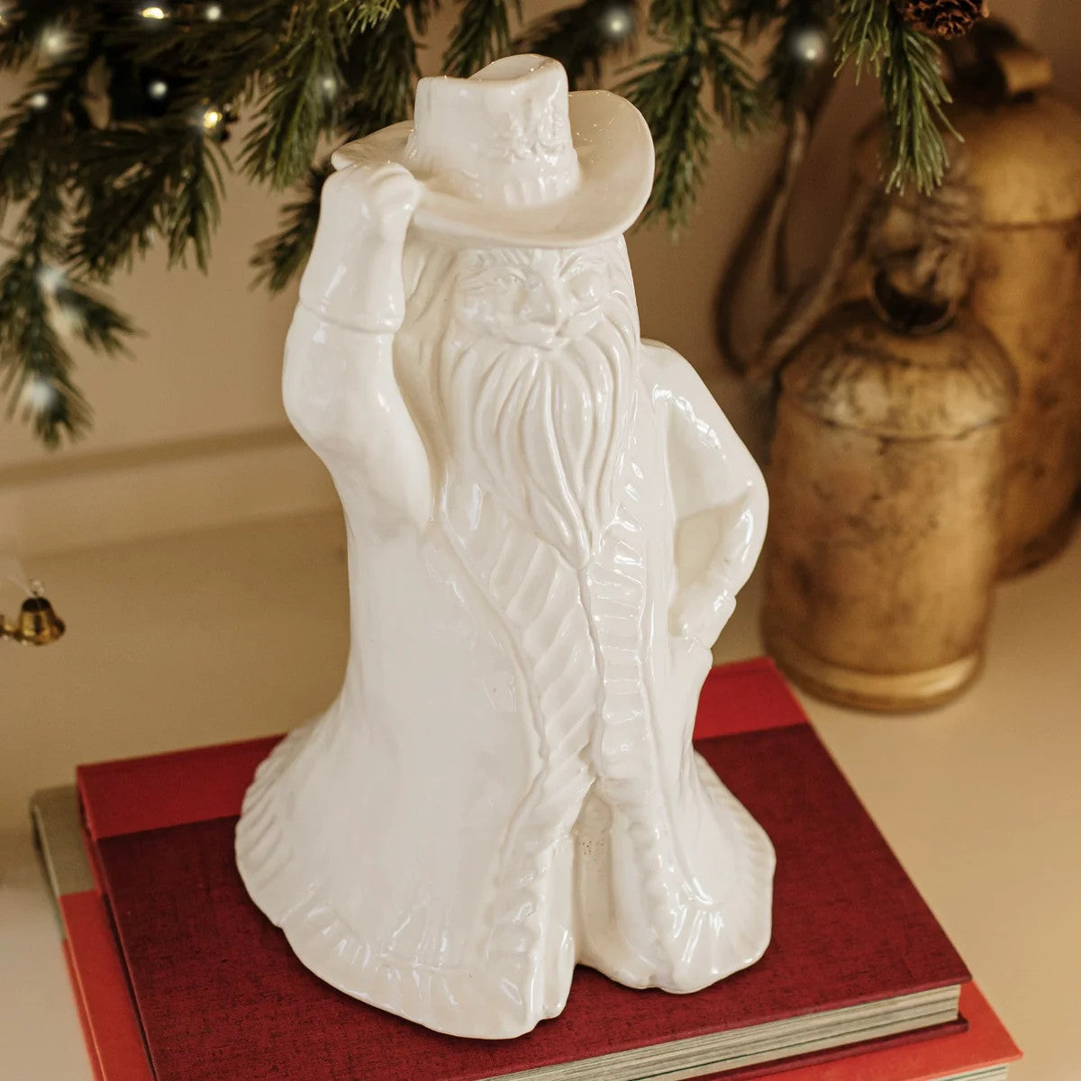 White ceramic Pietra Natale Figural Cowboy Santa figurine tipping his hat on a stack of red books.