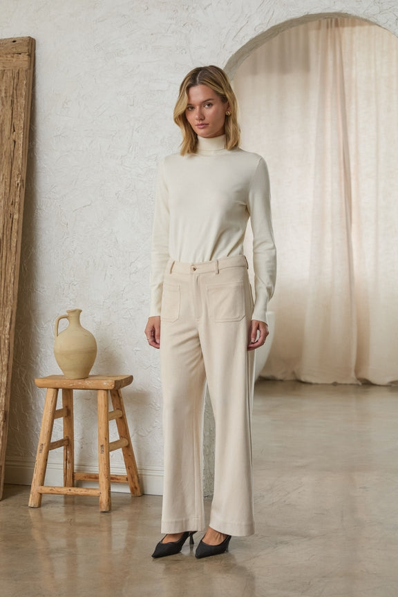 Woman wearing cream Lucy Faux Suede Wide Leg Pants with front pockets and a white turtleneck.