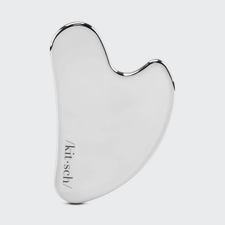 Stainless steel gua sha tool with smooth curved edges designed for facial massage.