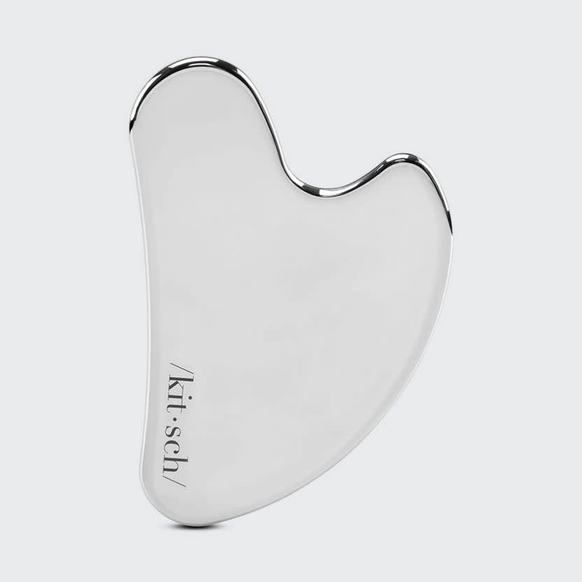 Stainless steel gua sha tool with smooth curved edges designed for facial massage.