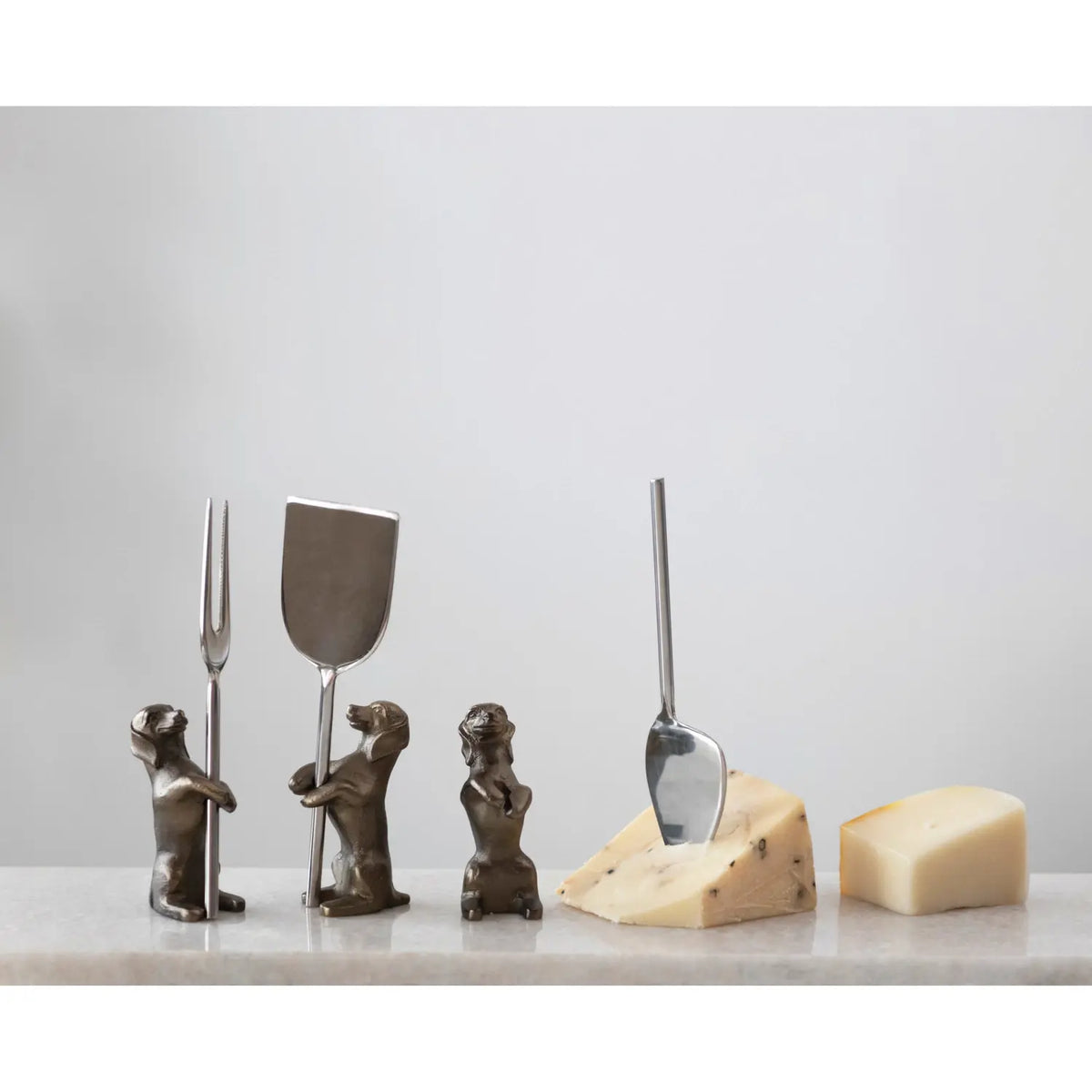 Stainless steel cheese serving knives with aluminum dog-shaped stands on a tray