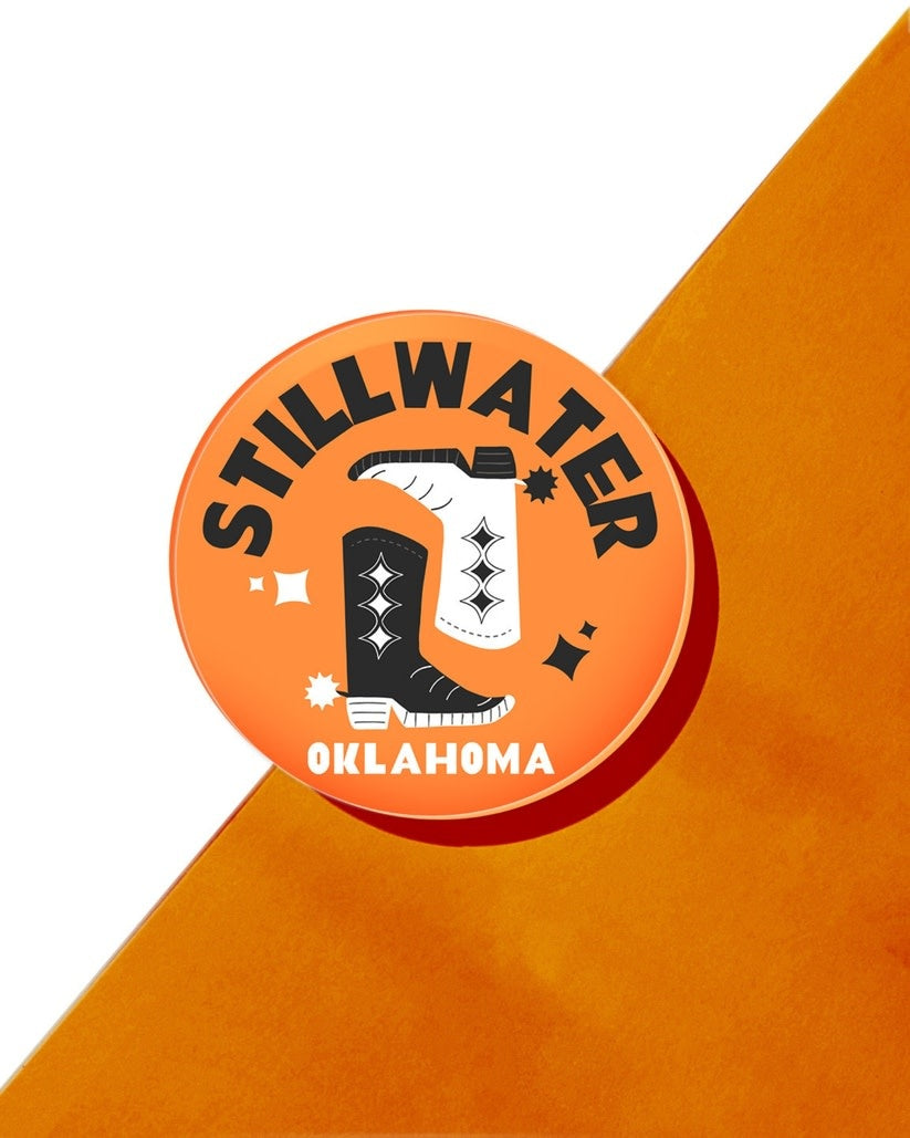 Four-inch round clear acrylic drink coaster with Stillwater Oklahoma text in navy blue.