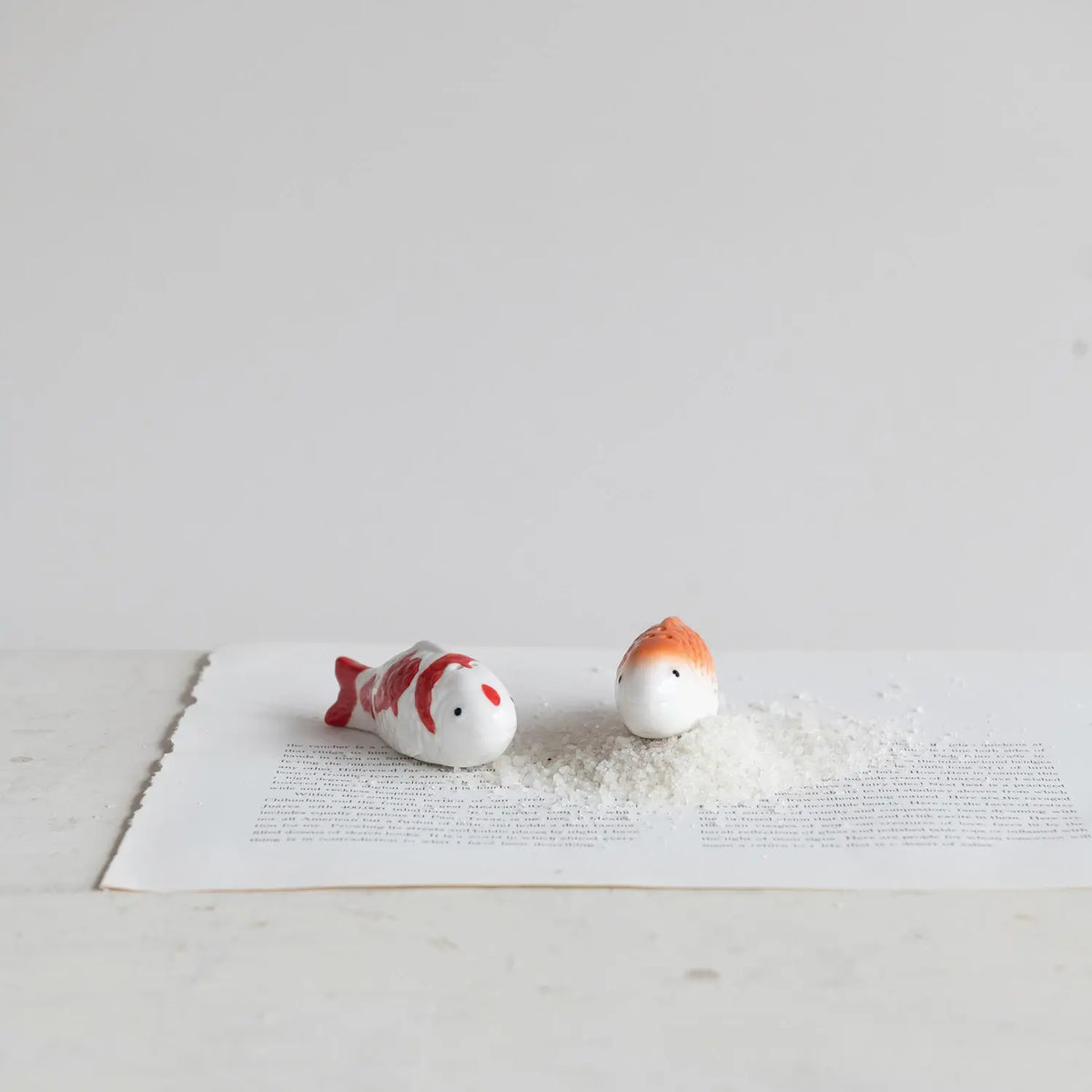 Stoneware salt and pepper shakers shaped as koi fish with detailed scales in earthy tones.