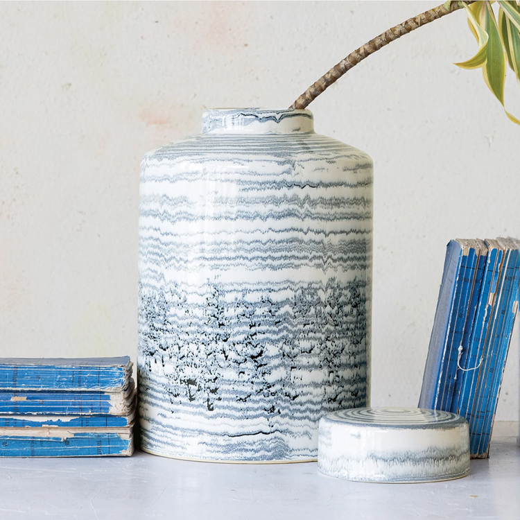 Round stoneware ginger jar with blue reactive glaze stripes on a white background and domed lid.