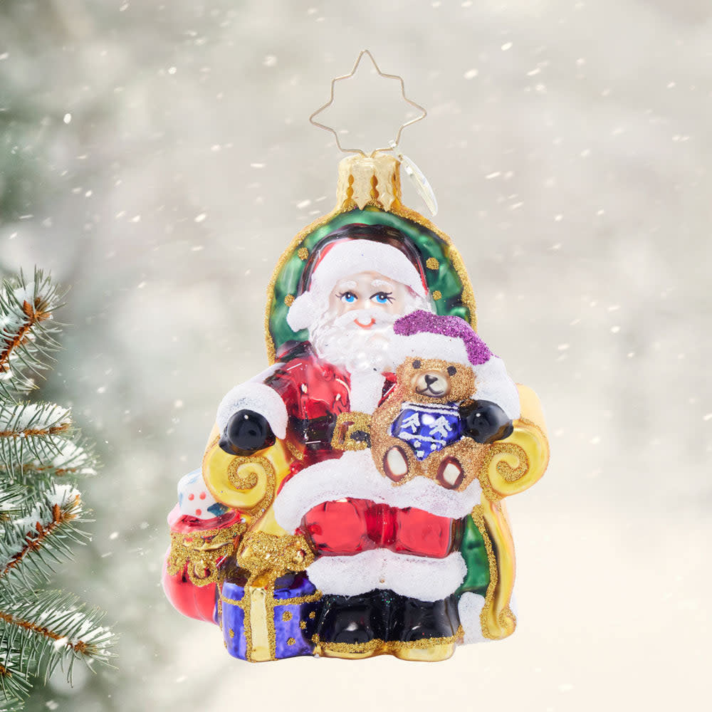 Small red gem-shaped Santa figurine with white beard holding a green gift box.
