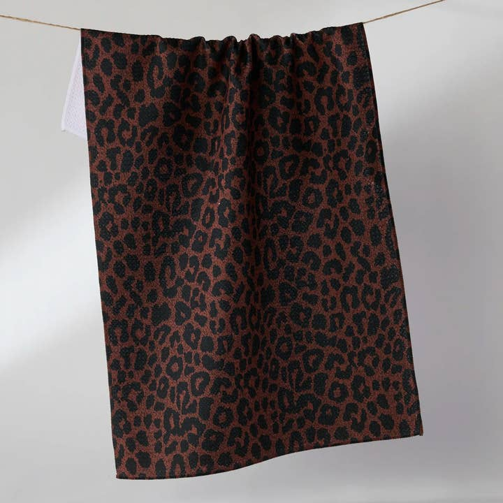 Halloween tea towel with a brown and black leopard print pattern hanging on a line.