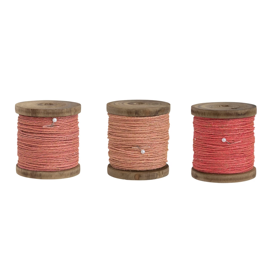 Wood spool holding jute cord with gold metallic thread