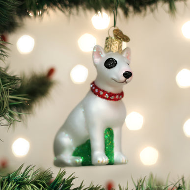 White Bull Terrier glass ornament with a black eye patch and red collar on a Christmas tree.