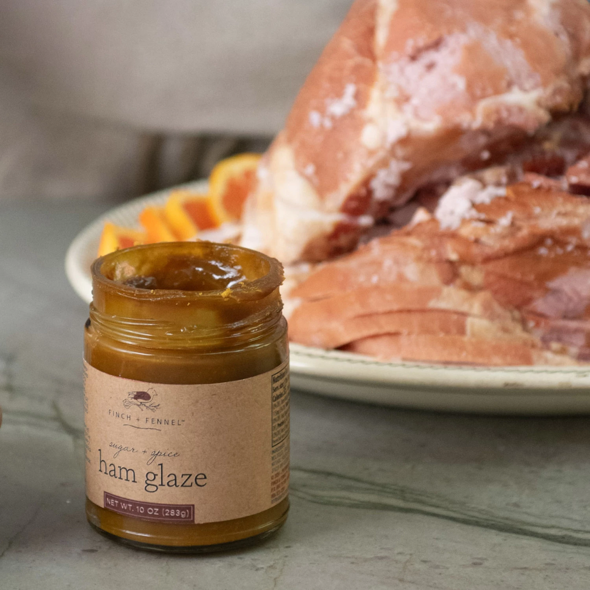 Bottle of Sugar + Spice Ham Glaze with brown sugar glaze on a ham