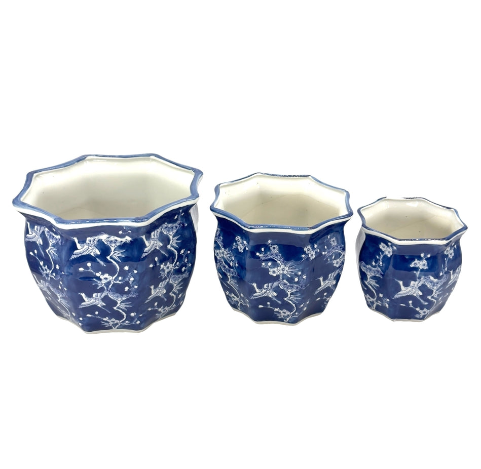 Set of three fluted blue and white ceramic Chinoiserie planter pots with crane and floral motifs.