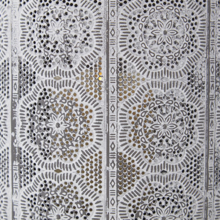 Close-up of whitewashed punched metal lantern featuring intricate floral medallion patterns.