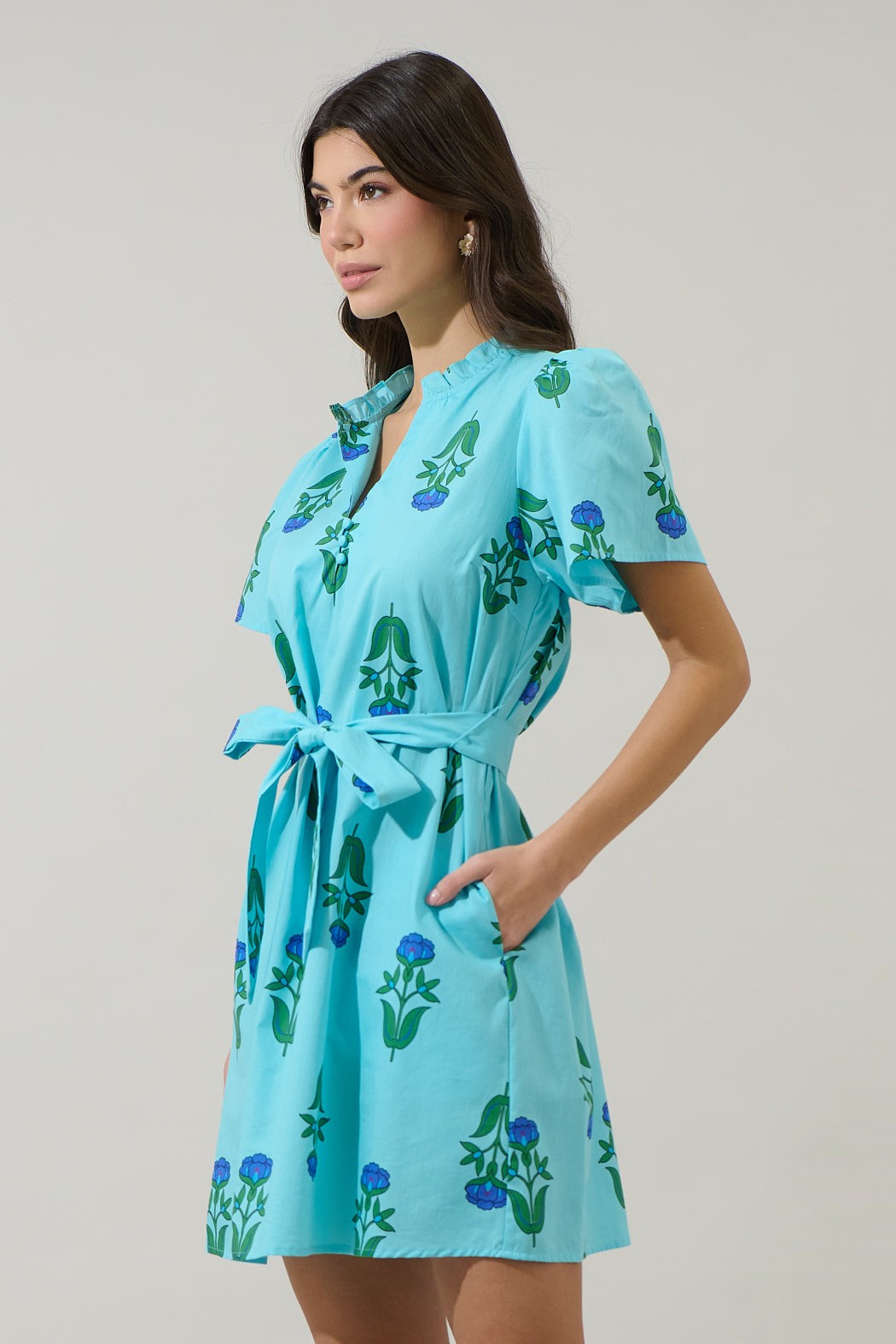 Woman wearing the Amena Floral Ema Shift Mini Dress in light blue with a belted waist.