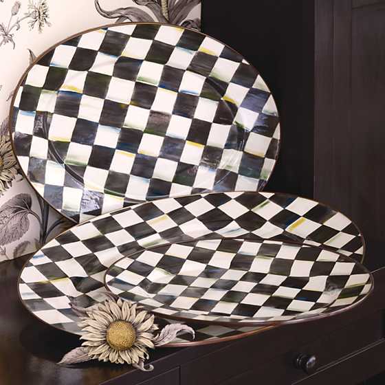 Three oval platters with hand-painted black and white Courtly Check patterns and bronzed rims.
