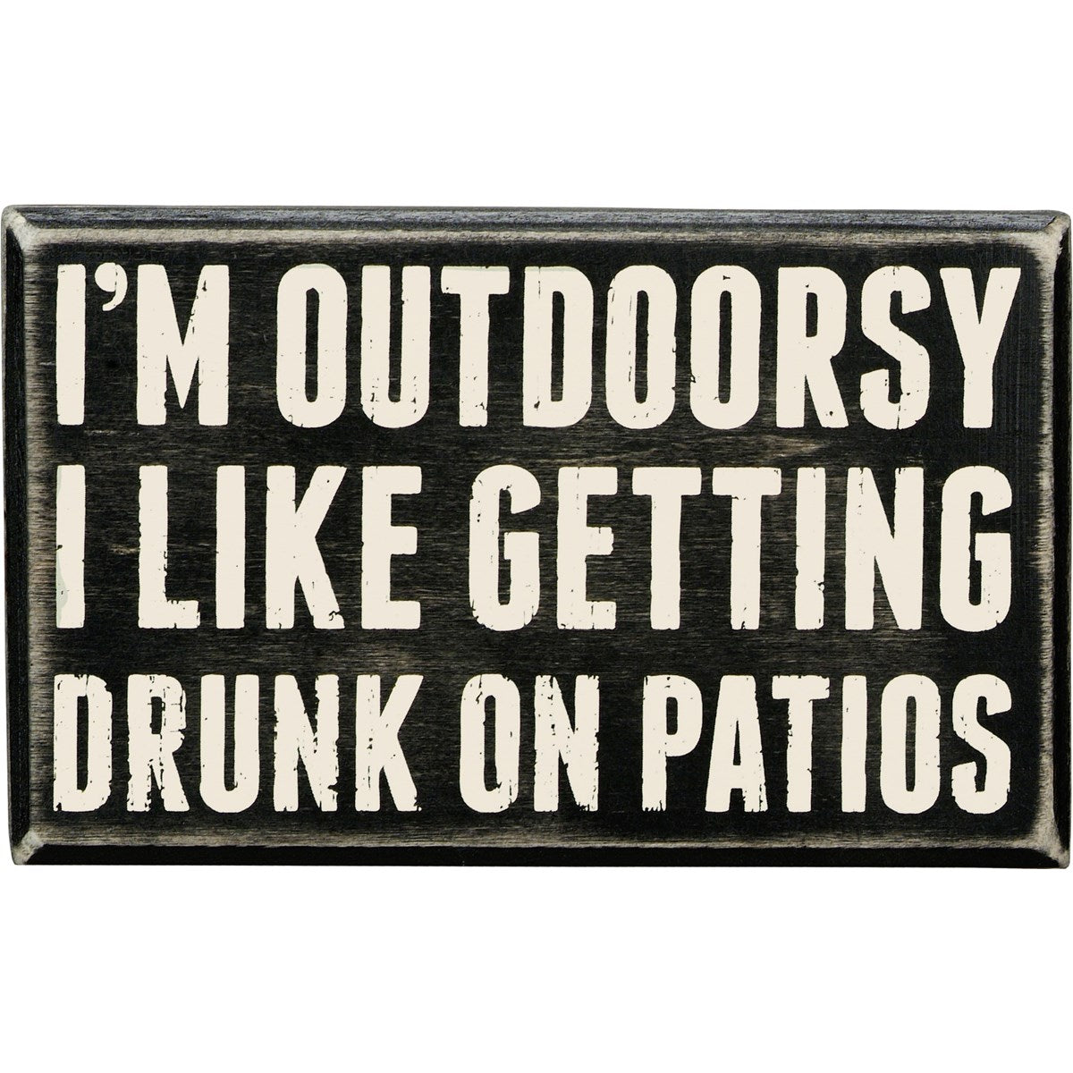 Black wooden box sign with white text that reads "I'M OUTDOORSY I LIKE GETTING DRUNK ON PATIOS."