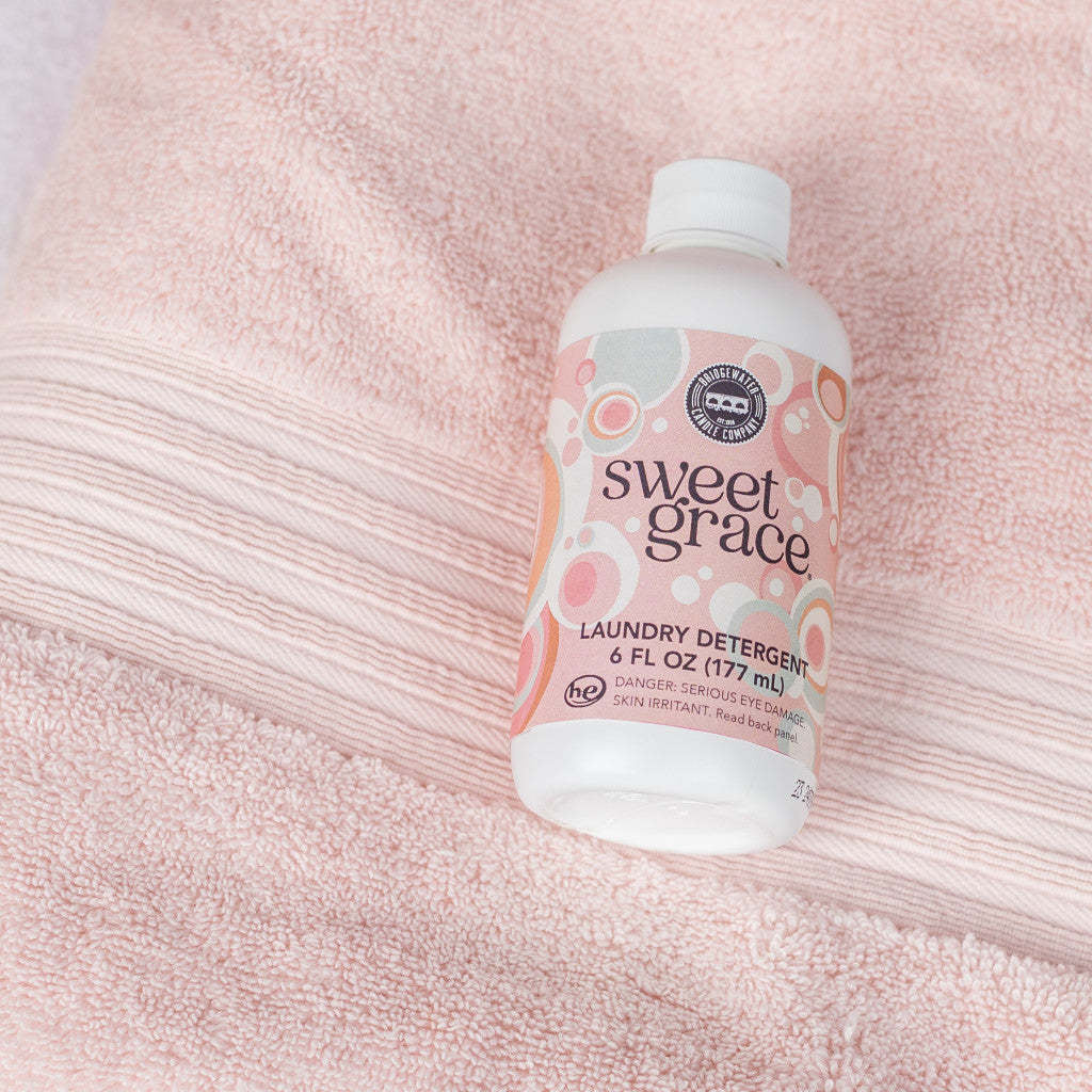6 oz bottle of Sweet Grace laundry detergent with a white label featuring exotic passion fruit and patchouli scent details.