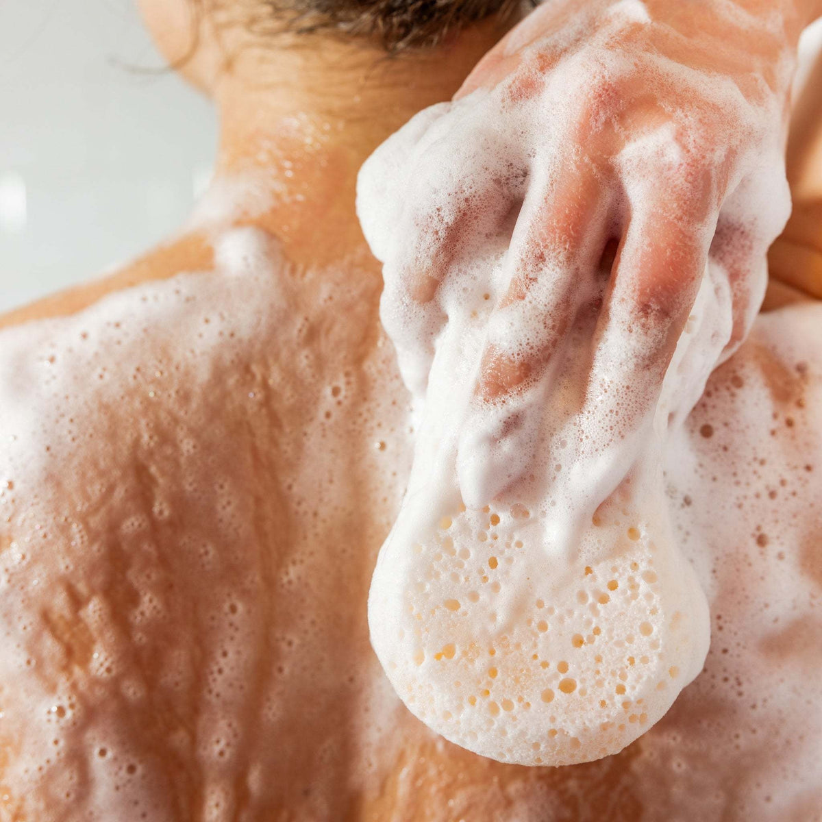 Sweet Grace body wash sponge with creamy lather texture in a soft pastel pink hue.