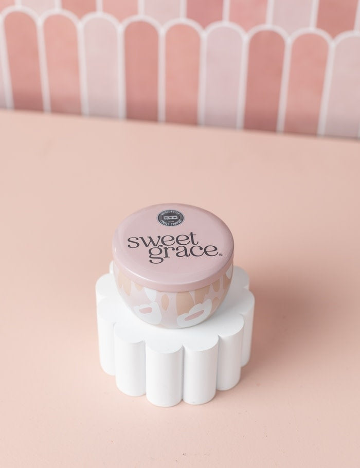 Travel-sized tin candle in blush, grey, and white with a playful pattern.