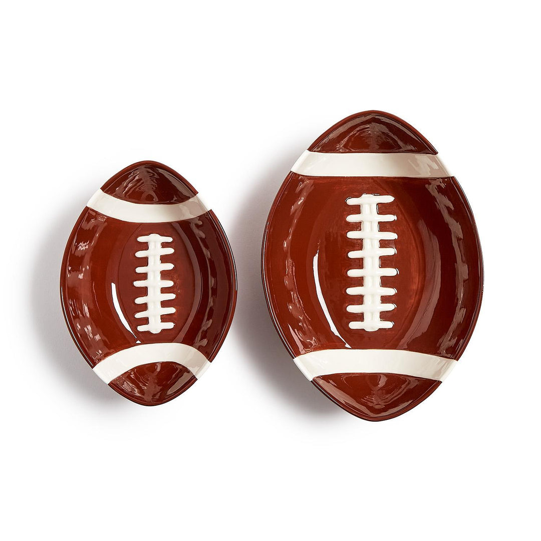 Two brown ceramic football-shaped tidbit bowls with white laces and stripes in different sizes.