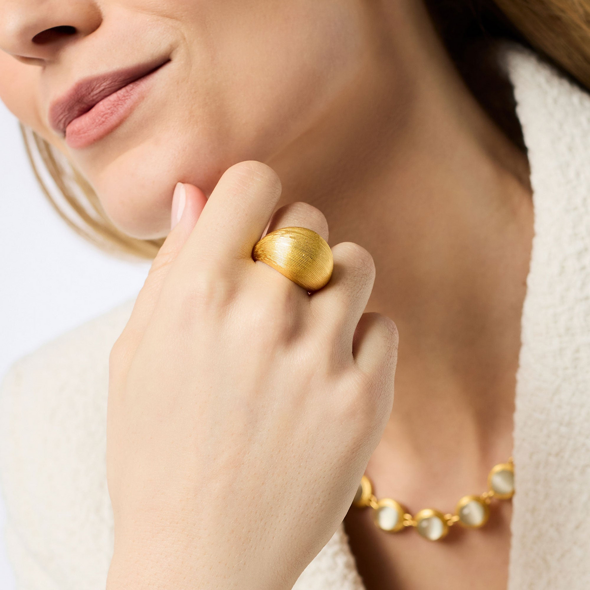 Woman wearing a bold, textured 24K gold plate Cobblestone Bombé Ring on her ring finger.