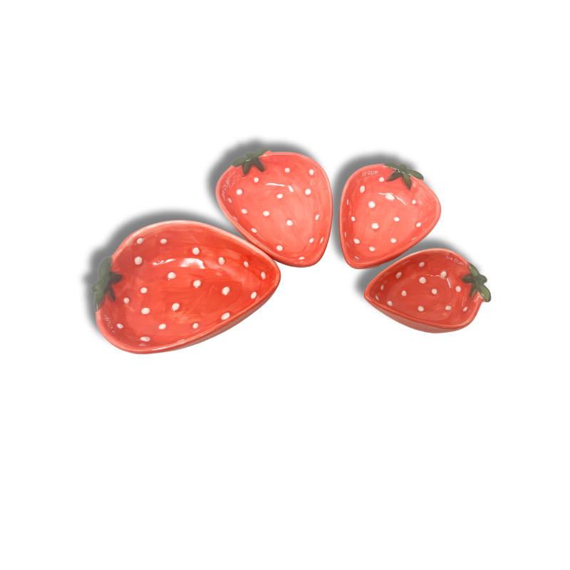Set of stoneware measuring cups shaped like strawberries with hand-painted red patterns.