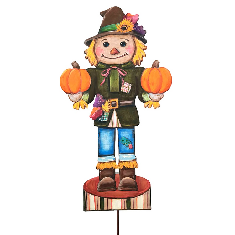 Hand-painted scarecrow nutcracker garden stake holding two pumpkins and wearing a brown hat.