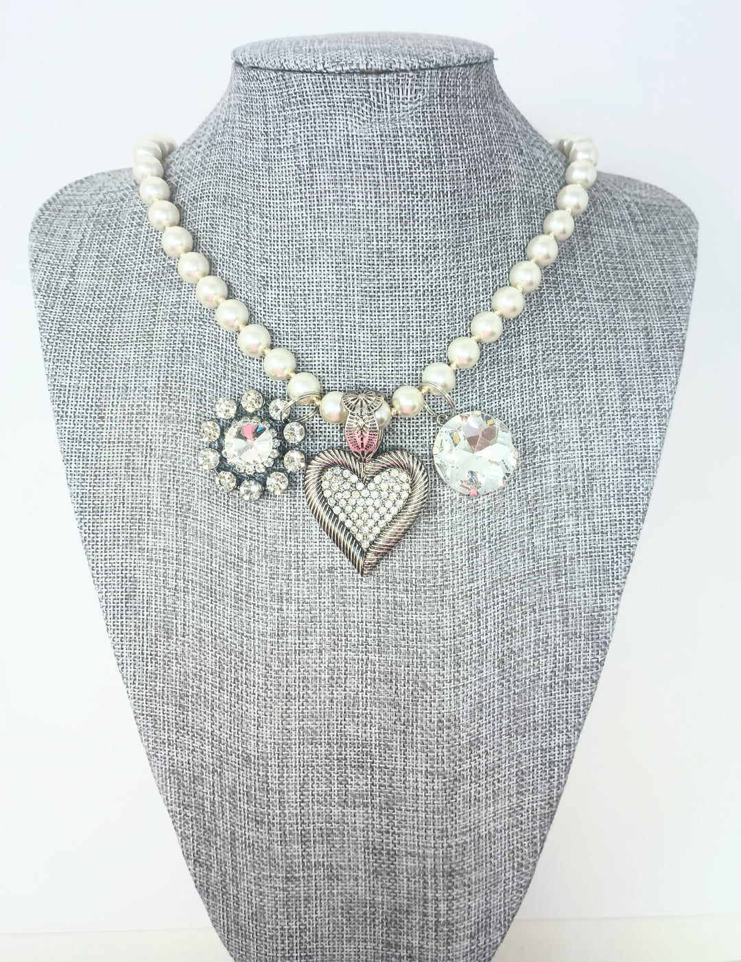 Fashion pearl necklace with three charms: a rhinestone flower, a crystal heart, and a round gem.