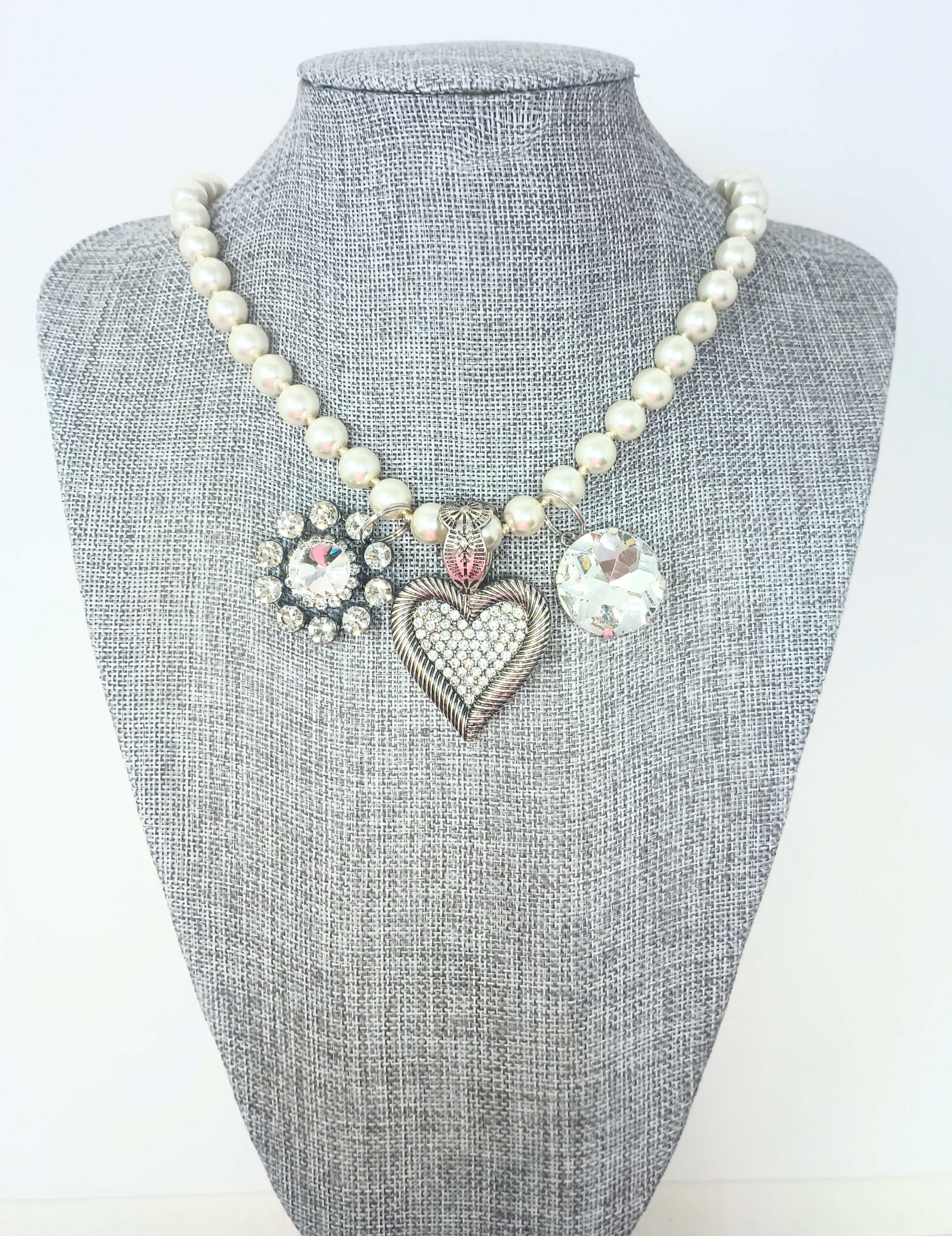 Fashion pearl necklace with three charms: a rhinestone flower, a crystal heart, and a round gem.