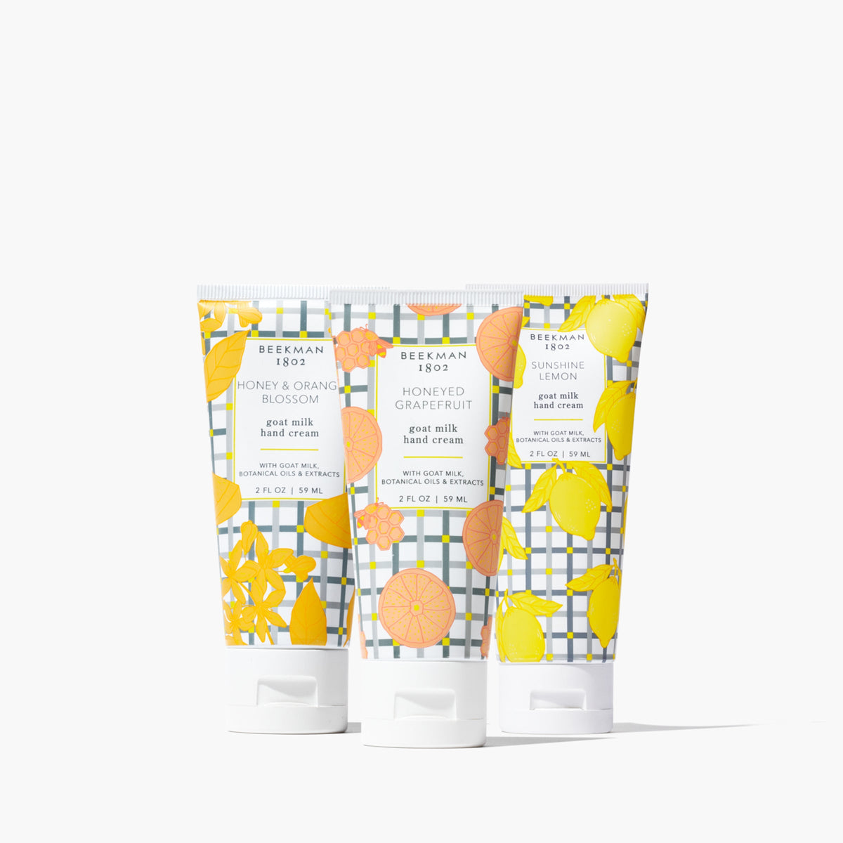 Three small hand cream tubes in honey, orange blossom, and lemon shades arranged together.