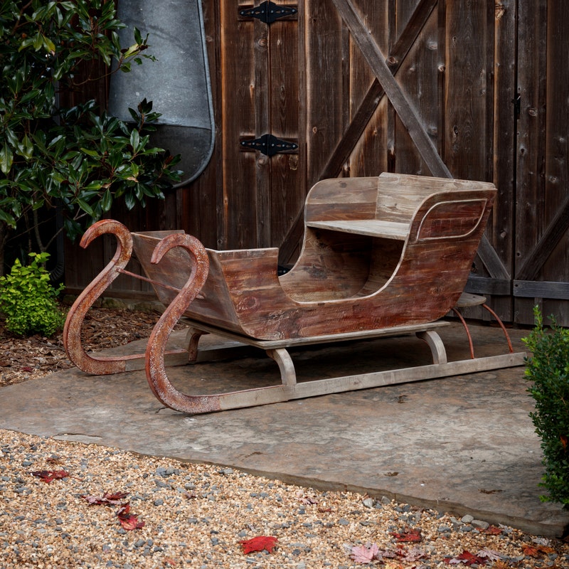 Life-sized vintage-inspired Grand Noel Sleigh made of weathered wood with curved metal runners.