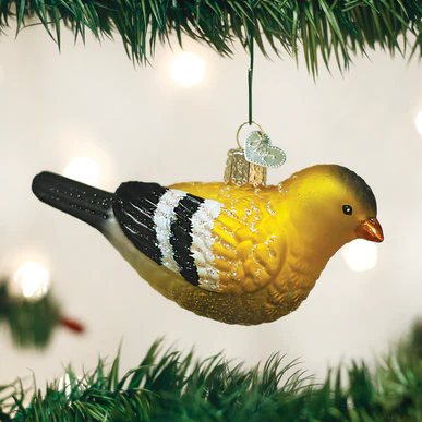American Goldfinch glass ornament with yellow body and black and white wings on a Christmas tree.