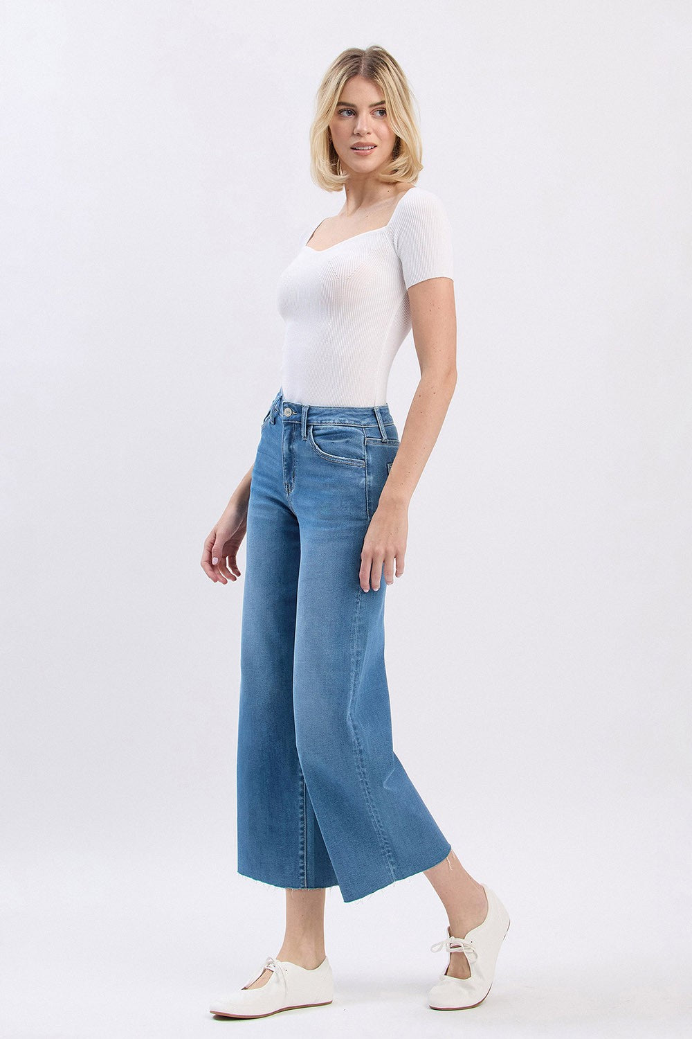 Woman wearing Audrey high rise slim wide leg cropped jeans with a raw hem in a light blue wash.