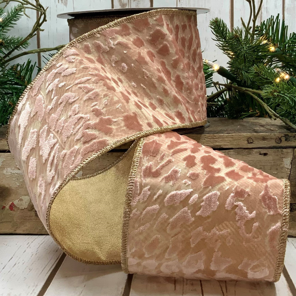 4-inch pink jacquard leopard print ribbon with gold wired edges on a wooden surface.