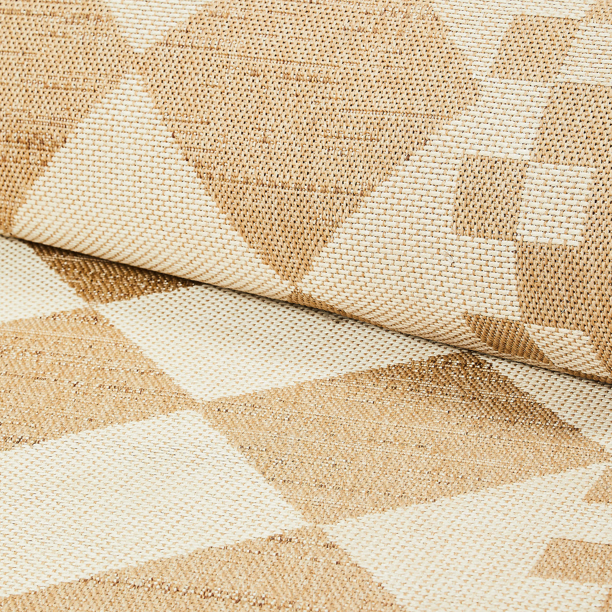 Close-up of a white and tan diamond pattern woven indoor/outdoor rug.