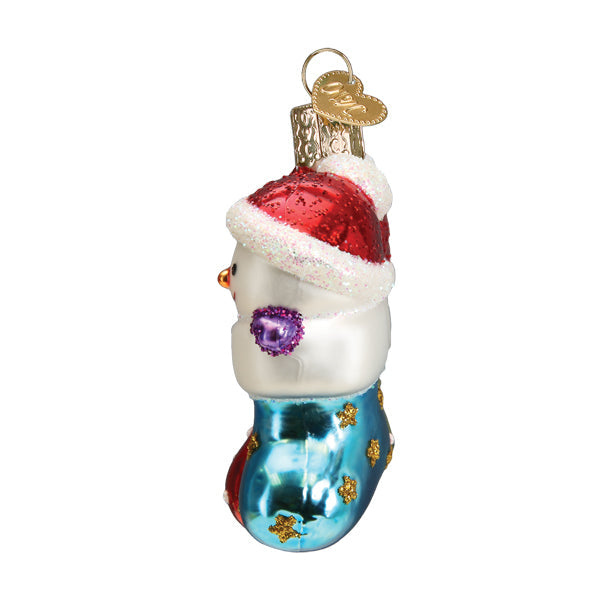 Side view of a glass snowman ornament wearing a red Santa hat and sitting in a blue glittered boot.