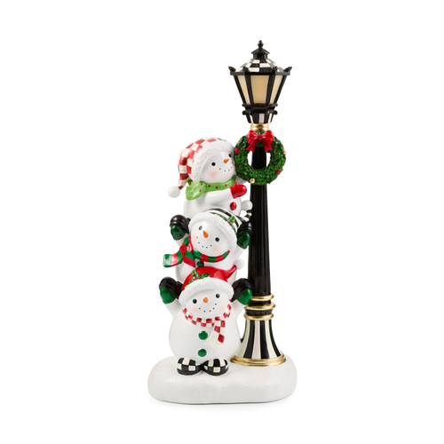 Illuminated figurine featuring three stacked snowmen next to a black and white striped lamppost.