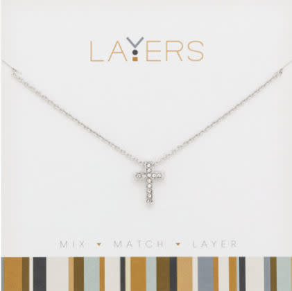 Silver necklace with a small cross pendant embellished with cubic zirconia stones on a display card.