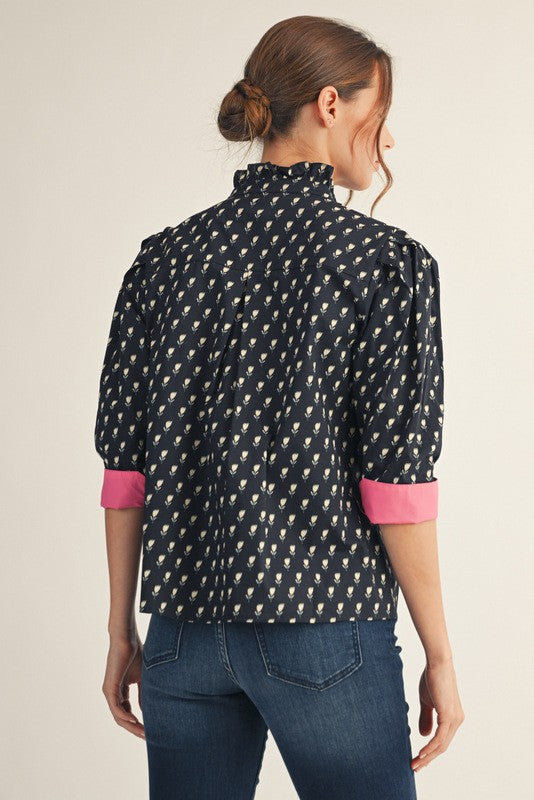Women's floral button-down top with ruffled neckline, solid contrast trim on three-quarter sleeves.