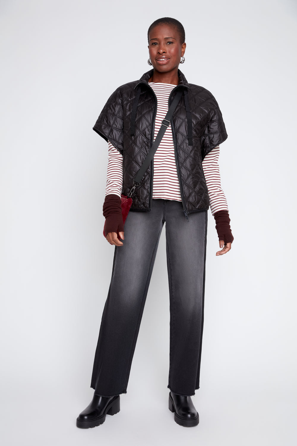 Model wearing the Megan Luxe Quilted Poncho in black over a striped top and grey jeans.