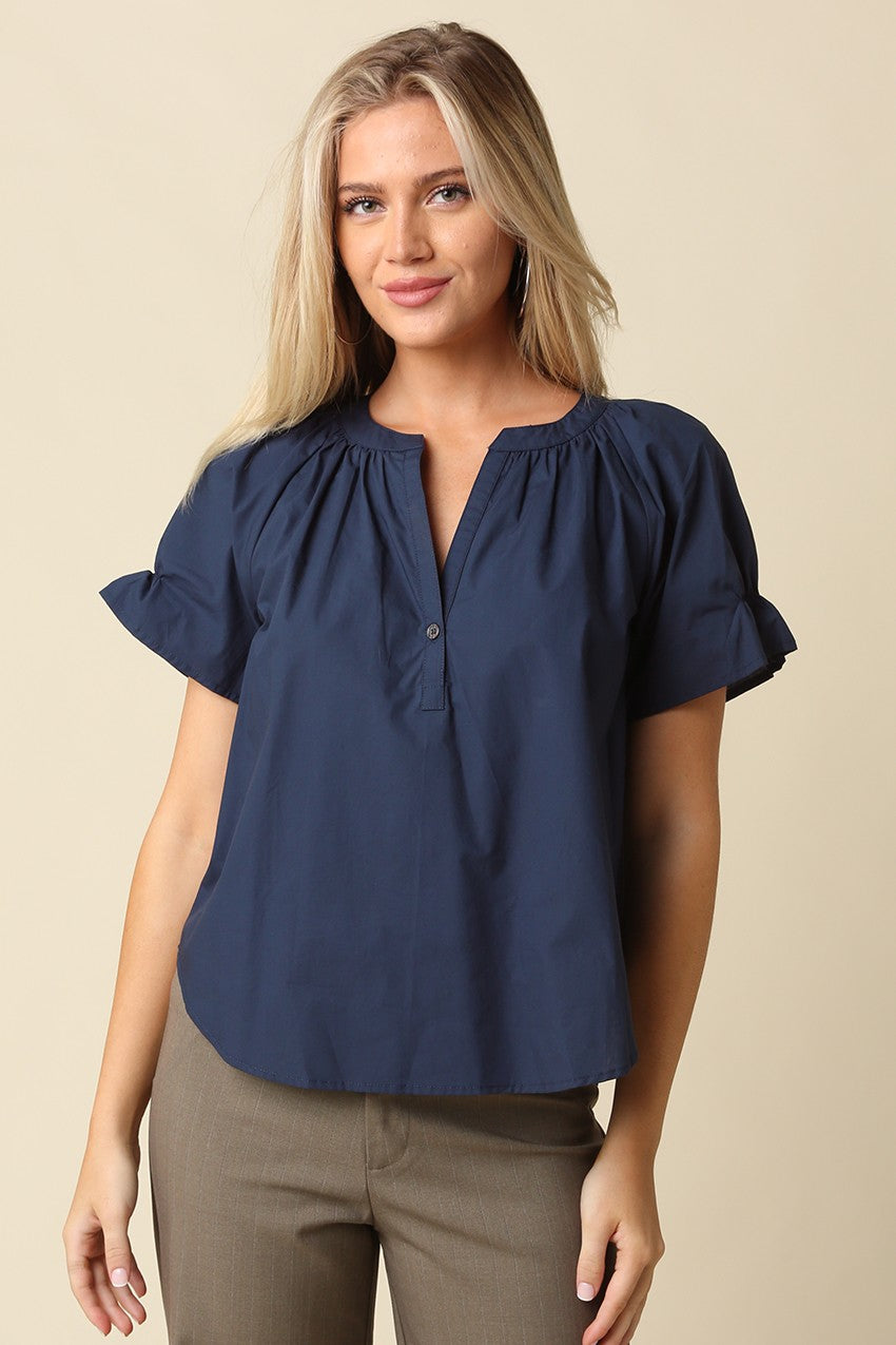 Woman wearing a navy blue Hylee Ruffle Sleeve Peasant Blouse with a split neckline and olive pants.