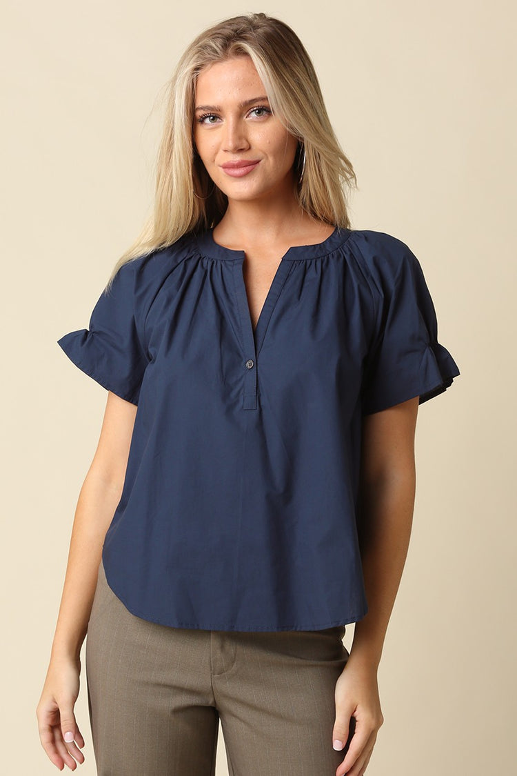 Woman wearing a navy blue Hylee Ruffle Sleeve Peasant Blouse with a split neckline and olive pants.