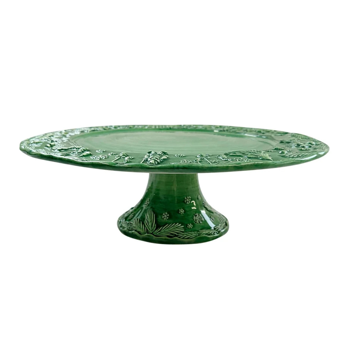 Green stoneware cake stand with hand-sculpted holiday scenes and a decorative pedestal base.