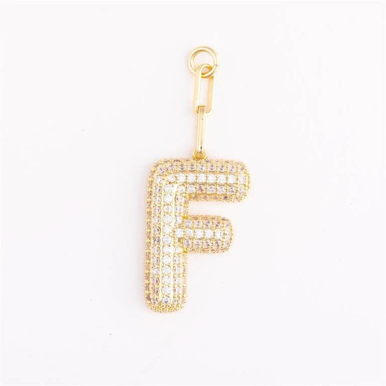 Heather-colored charm bag with gold plating, pave crystal accents, and a customizable initial on an extender chain.