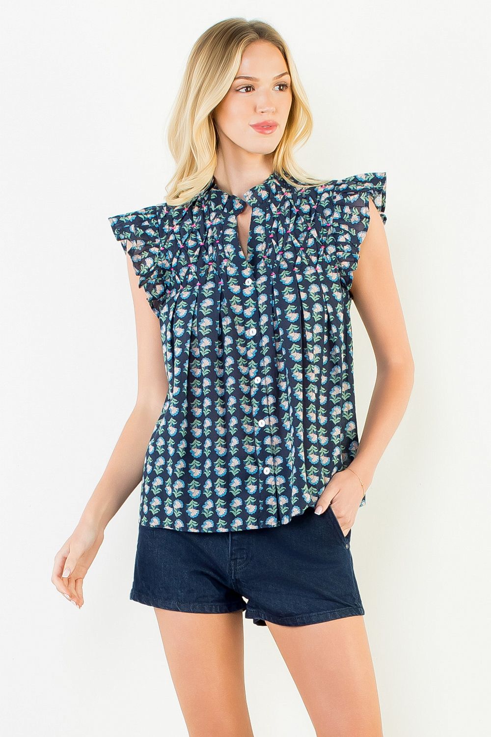 Woman wearing the Jane Flutter Sleeve Button Top in a navy floral print with dark denim shorts.