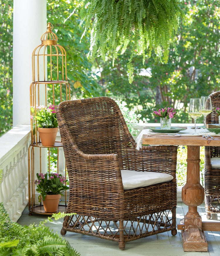 La Voliere golden steel stacking etagere shaped like a birdcage holding potted plants on a porch.