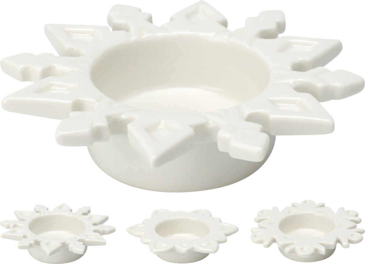 Tealight holder with a delicate white snowflake cutout pattern on a clear base.