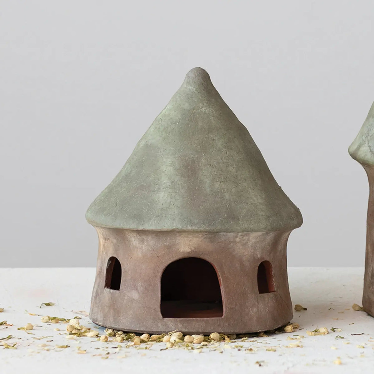 Terracotta decorative toad house with green roof accents on a natural background.