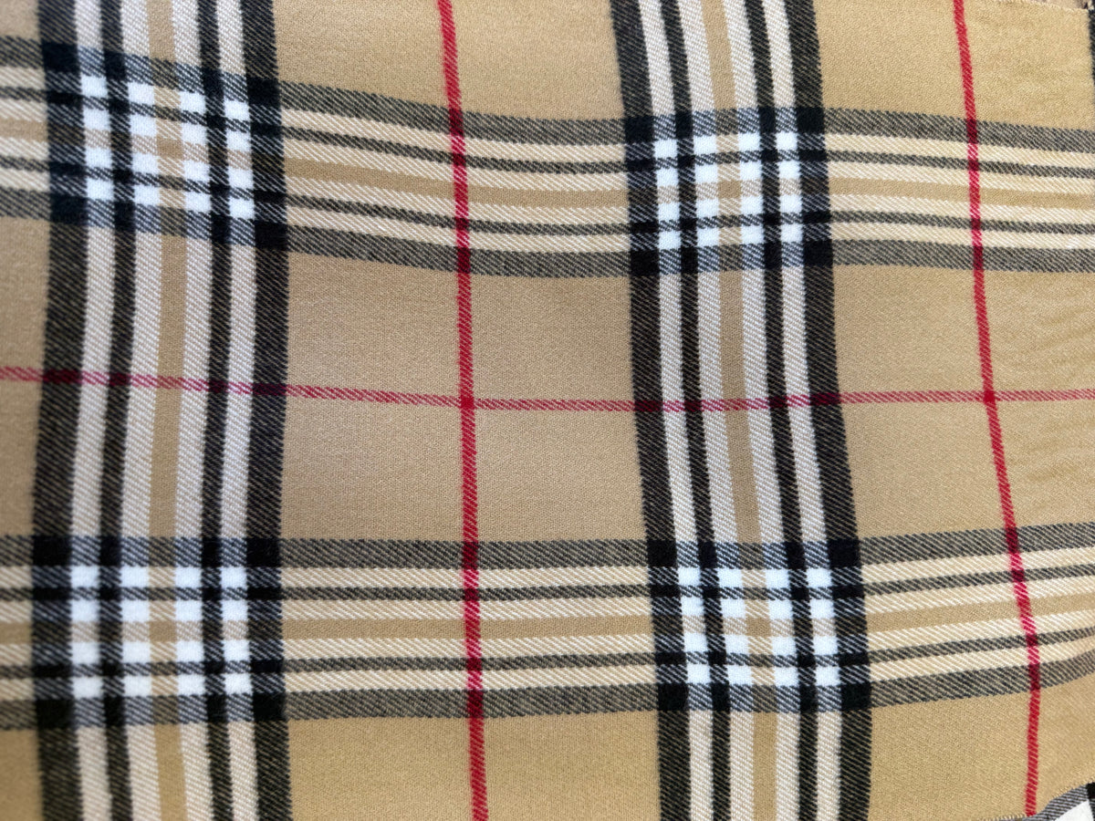 Close-up of a tan Scottish plaid cashmere scarf with black, white, and red stripes.