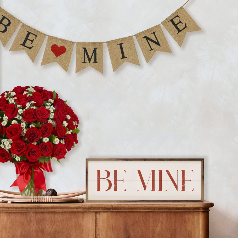 Red Be Mine On White framed wood sign on a wooden dresser with roses and a banner.