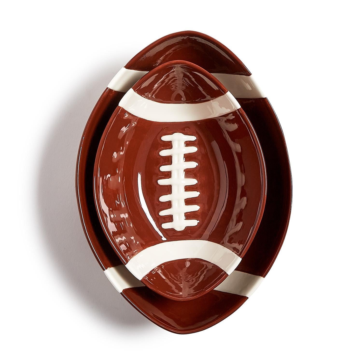 Two nested football-shaped ceramic tidbit bowls in brown with white stripes and laces.
